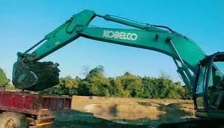 KOBELCO excavator loading soil on tractor mud